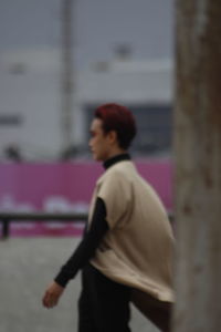 Side view of woman standing against wall