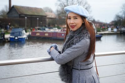Portrait of young woman standing at lake during winter in city
