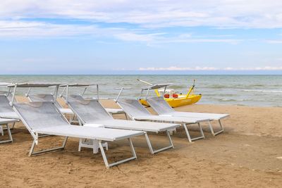 Chairs on beach against sky