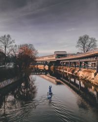 Man on footbridge over river against sky