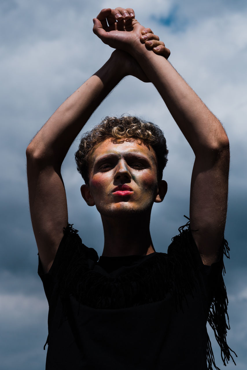 PORTRAIT OF YOUNG MAN STANDING IN FRONT OF SKY