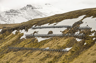 Construction on a partly snow-covered mountain slope to protect an icelandic town against avalanches
