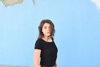 Portrait of beautiful woman standing against blue wall