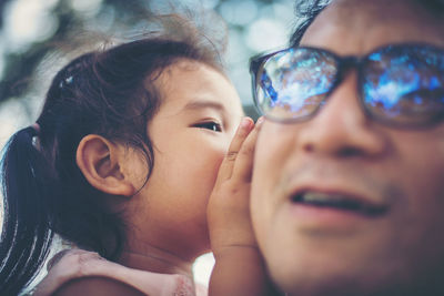 Close-up of daughter whispering in ear of father