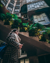 Side view of young woman standing by building in city