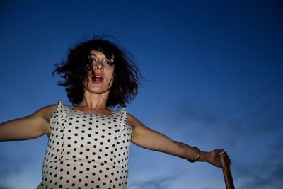 Portrait of beautiful woman standing against blue sky