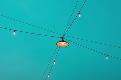 Low angle view of illuminated lights against clear blue sky