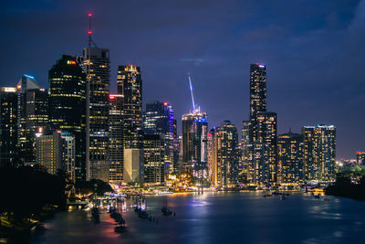 Illuminated buildings in city against sky at night