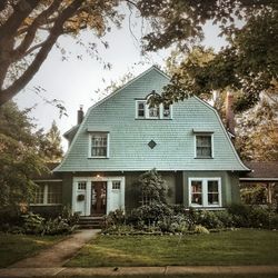 House and trees by building against sky