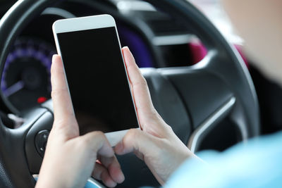 Midsection of man using mobile phone in car