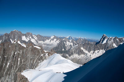 Scenic view of snowcapped mountains against clear blue sky