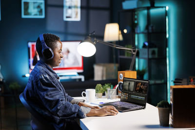 Rear view of woman using laptop at table