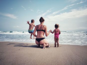 Rear view of family at beach against sky