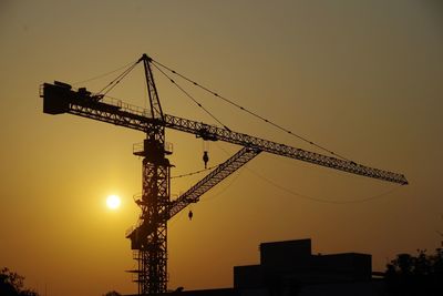 Low angle view of crane at sunset