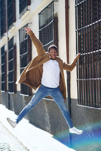 Full length of young man jumping against built structure