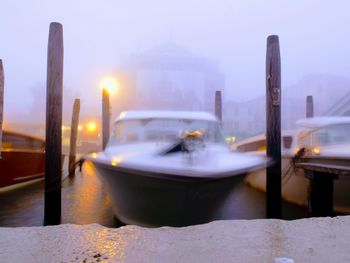 Boats moored at illuminated city against sky at night