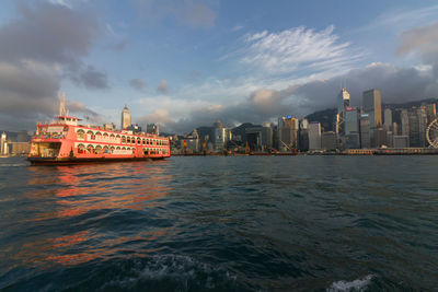 View of city at waterfront against cloudy sky