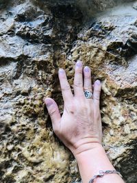 Cropped hand of woman touching rock