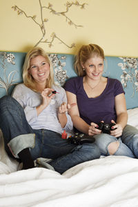 Two young women playing video game in bedroom