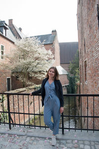 Smiling beautiful young girl stands on the old bridge under blossoming trees