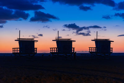 Silhouette hut on beach against sky during sunset