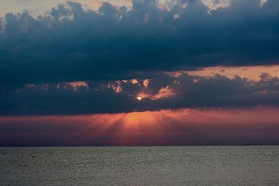 Scenic view of sea against dramatic sky during sunset