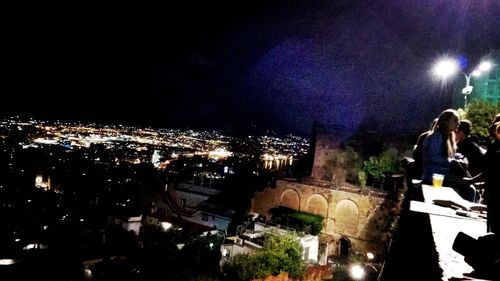 Illuminated cityscape against sky at night