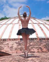 Full length rear view of woman standing against wall