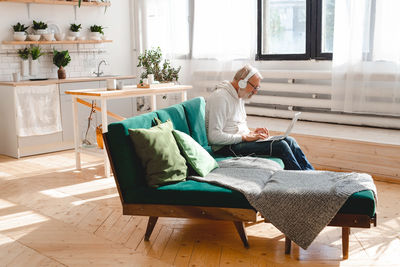 Young woman using digital tablet while sitting on sofa at home