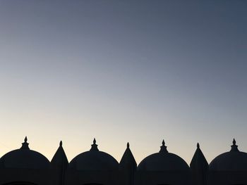 Low angle view of silhouette buildings against clear sky