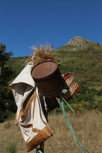 Bag and basket with rusty container on pole at field