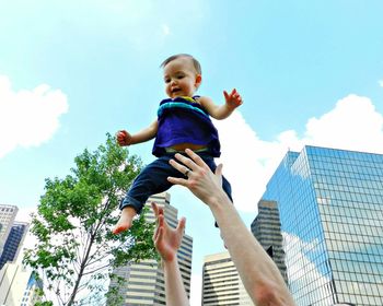 Low angle view of girl standing against cloudy sky