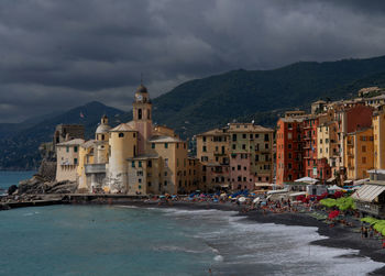 Buildings by river against sky