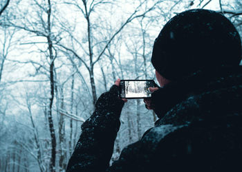 Full length portrait of man holding smart phone in winter