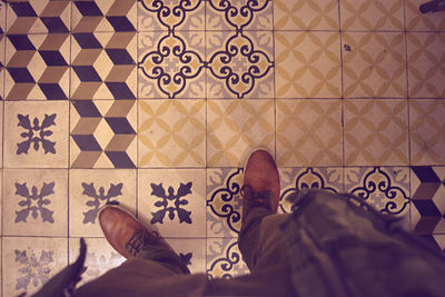 Low section of man standing on tiled floor