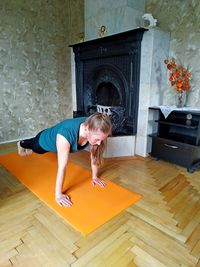 Girl doing plank at home on an orange yoga mat