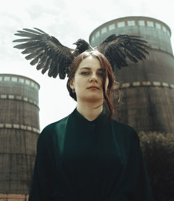 Portrait of young woman flying against building