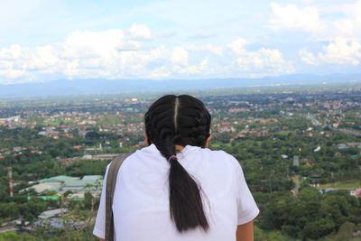 Rear view of man looking at cityscape against sky