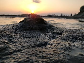 Surface level of beach against sky during sunset