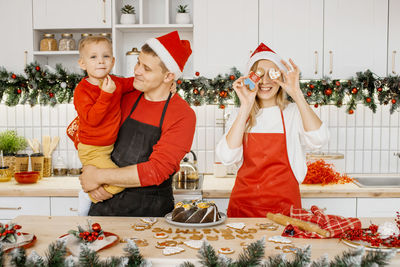Portrait of happy friends holding christmas tree