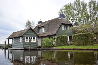 Houses by lake against sky