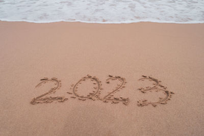 New year 2023 is coming with sunset beach background. 