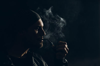 Man smoking cigarette against black background