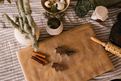 Ginger cookie molds, rolling pin, cinnamon sticks and christmas decor on the table in a cozy kitchen