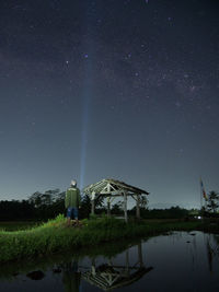 Man standing by lake against sky at night