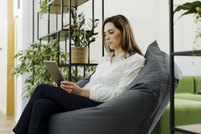 Young woman using phone while sitting on chair