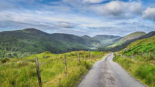 Road leading towards mountains against sky