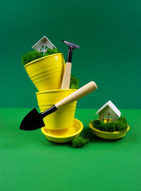 Creative photo on a green background with yellow flower pots and garden tools