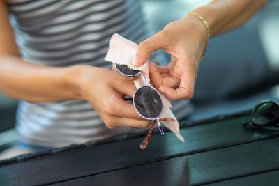 Midsection of woman cleaning sunglasses