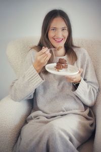 Portrait of smiling young woman having breakfast on bed at home